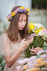 Asian girl using a smartphone photographing flowers in the flower garden
