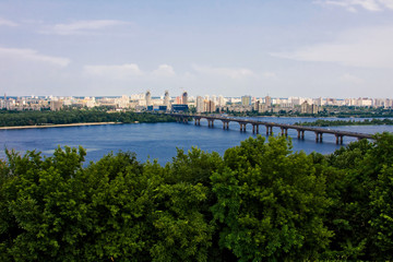 Forest, river, bridge, city in the distance under the sky