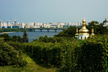Fototapeta na wymiar City, green trees, sky, church, river and bridge in the distance