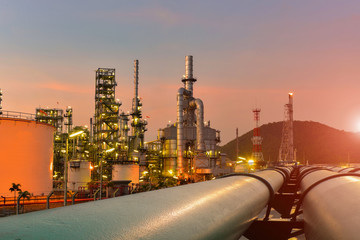 Oil refinery plant near oil tanker storage or power plant with pipe line trasport on sunset, twilight bacckground.