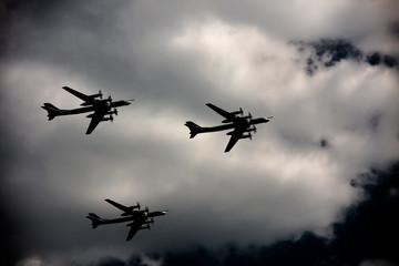 Fototapeta na wymiar Three bombers fly against the sky in the shadow