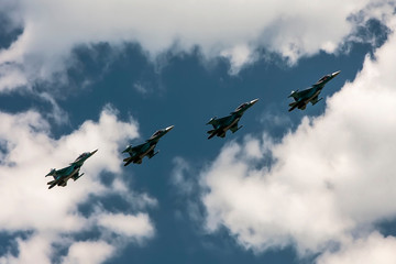4 combat aircraft against a blue sky and clouds