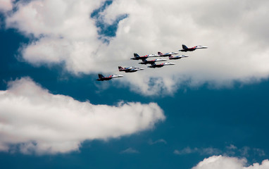 A lot of planes are flying against the sky and clouds.