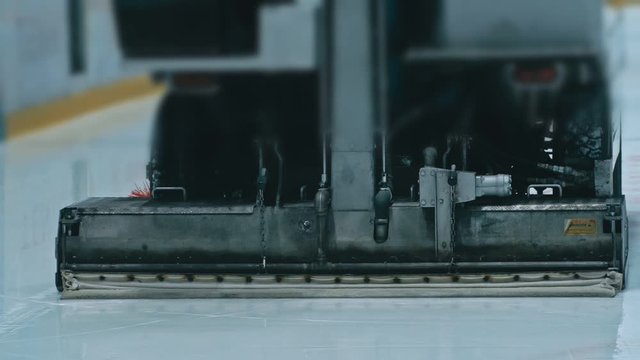 Zamboni resurfacing an indoor skating rink. Slow Motion. Ice resurfacer cleaning ice, machine cleaning and polishing smooth icerink. Ice harvester or restores ice.