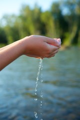 A girl's hand or a girl's hand holds clean river or sea water in the wild.