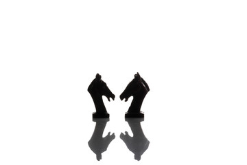 Silhouette of two vintage horses chess isolated on white background with reflection on the floor