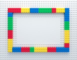 Frame of colorful toy bricks on white construction plate with place for your content. 3d rendering
