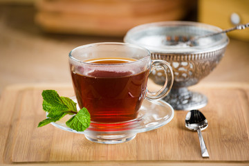 Moroccan tea with mint and sugar in a glass on a white table with a kettle