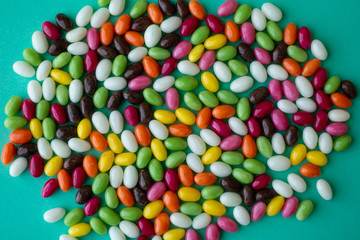 Easter candies in egg form in white, brown, yellow, green, pink and orange colors on green-blue background. Selective focus, Easter background. Easter sweets.