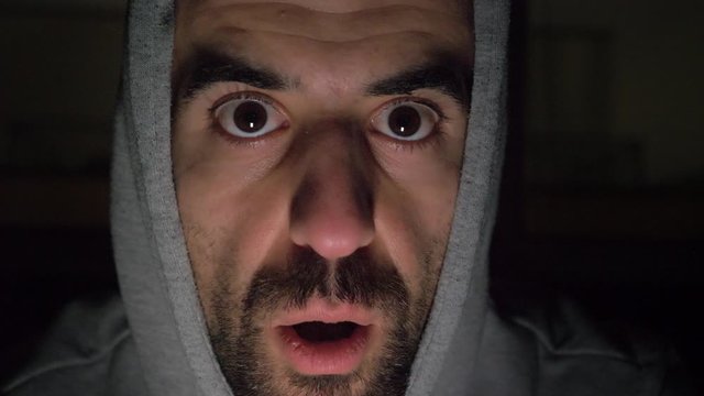 Spooky man whispering to camera and looking around scared