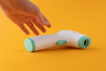 a female hand holds a thermometer on the scoreboard the numbers 36.6 degrees Celsius are visible, on a yellow background, close-up