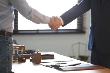 Male lawyer shaking hands with client in office, closeup - obrazy, fototapety, plakaty