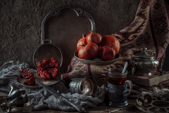 Still life with pomegranates. Oriental flavor. Horizontal format. Ceramic jugs with wine.