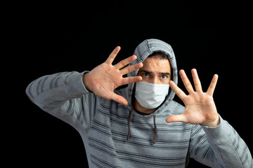 Young man in a gray hoodie and mask to prevent coronavirus posing