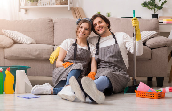 Portrait Of Happy Couple Sitting On Floor After Spring-Cleaning At Home