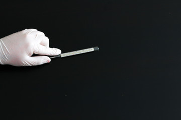 A hand in a medical glove holds a thermometer