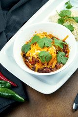 Traditional Mexican cuisine dish - chili con carne. spicy stew containing chili peppers,meat and tomatoes and beans with cheddar and rice