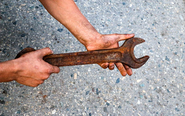 big old rusty wrench is held by male dirty calloused hands.