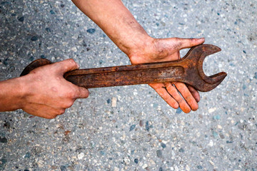 big old rusty wrench is held by male dirty calloused hands.