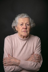 Pensive portrait of a grandmother. The concept of seniority and the elderly. Model grandmother in the studio on a black background.