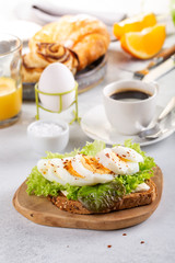 Delicious breakfast with boiled egg on toasted bread, cup of coffee and orange juice.