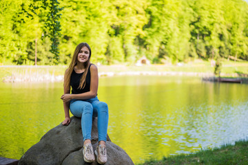 Shy girl sanding looking at camera . Cute teenage girl being shy on lake background