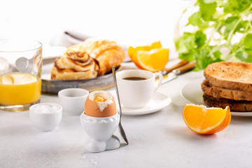 Delicious breakfast with soft boiled eggs, toasted bread, cup of coffee and orange juice.