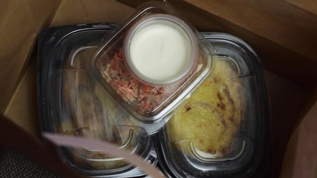 Take-away food in a paper bag with plastic containers and potatoes