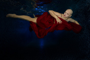 Girl without hair is happy, underwater photo, remission of a bald girl