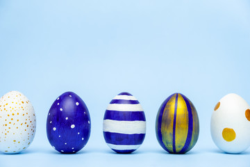 Five easter trendy colored classic blue and golden decorated eggs striped pattern on blue. Happy Easter card with copy space for text. Minimal style.