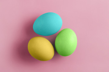 Three fresh coloured chicken eggs on a pink background. Minimal Happy Easter concept decoration. Copy space for text mockup