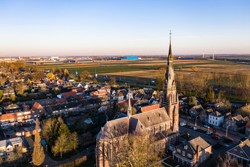 A church and windmills during sunrise on a sunny morning in the dutch town of Waalwijk, Noord Brabant, Netherlands