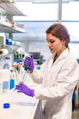 Girl scientist pours liquid in flask with pipette