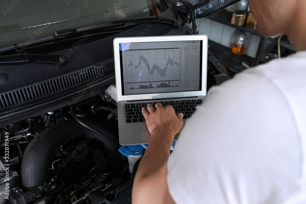 Wall mural Mechanic with laptop doing car diagnostic at automobile repair shop, closeup