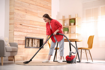 Young woman using vacuum cleaner at home