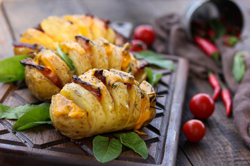 A summer lunch. Baked potatoes with bacon, cheese, tomato, chili peppers and herbs on a wooden board. Rustic. Background image, copy space