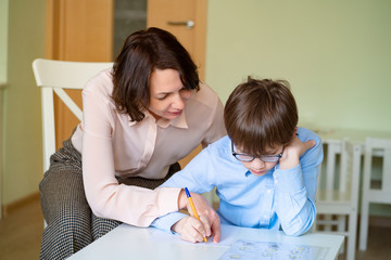 Fototapeta premium mom helps son to do homework. teacher deals boy.