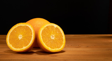 Halves oranges on a black background. Space for text. Sliced citrus fruits on a wooden table.