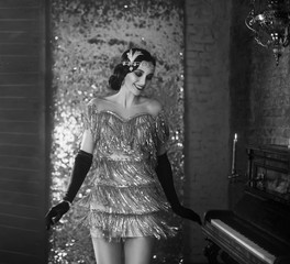 Young happy flapper beautiful woman. finger wave hairstyle headband. short sexy silver dress, smile face. model poses dances. backdrop old classic interior. Black and white photo. Style roar Party 20s