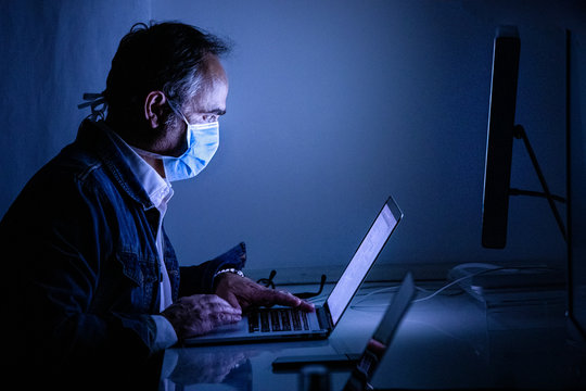 Impegato lavora al suo compuetr con la mascherina