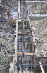 The beginning of house foundation construction: digging deep trenches for concrete foundation and installing the rigid structure of reinforcement iron, steel bars.