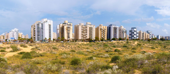 Obraz premium Panorama of a new residential area with modern houses and a large landscaping of the territory of the city of Holon in Israel. View from the sand dune.