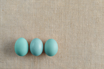 Top view of three bright painted easter eggs on canvas background. Colorful easter eggs decoration. Flat lay, top view. with copy space for text.