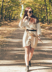  Stylish girl in glasses and a hat walks along a forest path