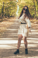  Stylish girl in glasses and a hat walks along a forest path