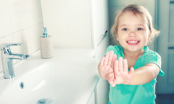 Child girl smiling face wahing and showing clean hands.