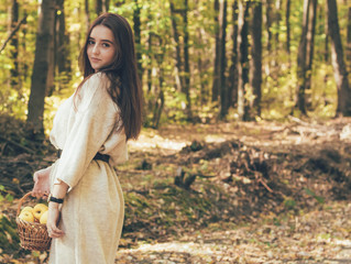 Girl in the forest holds a basket with apples