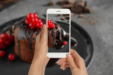 Food blogger taking picture of delicious warm chocolate lava cake at grey table, closeup