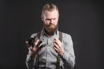 Handsome young man presents car parts on a gray background. The concept of sales and testing of goods