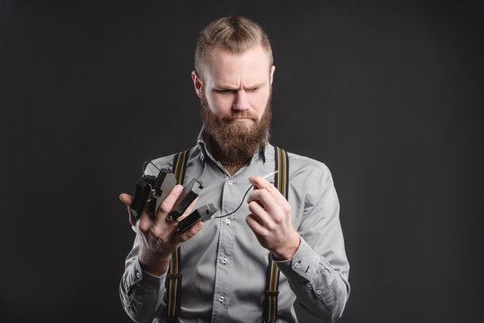 Handsome young man presents car parts on a gray background. The concept of sales and testing of goods